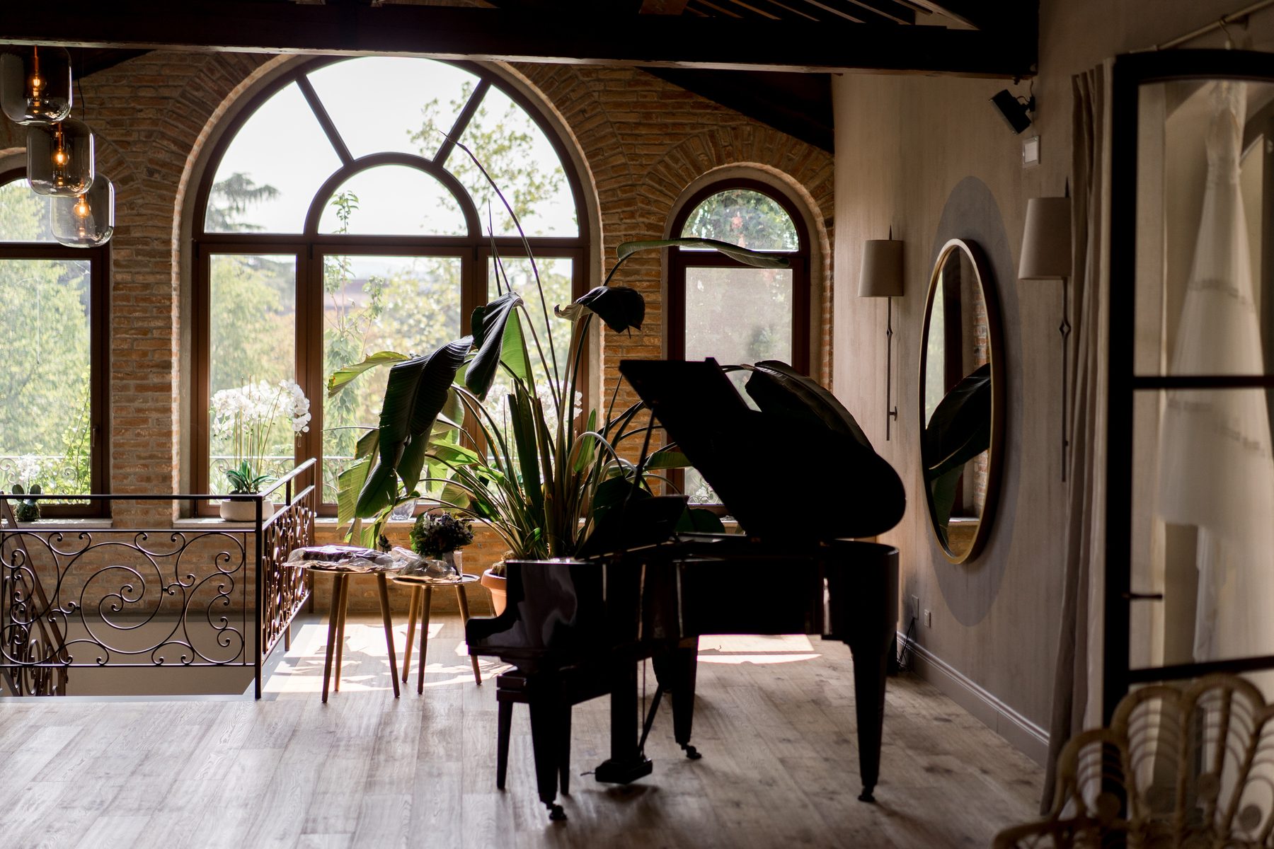 Il Salone con pianoforte a coda, finestre ad arco in mattoni e specchio tondo