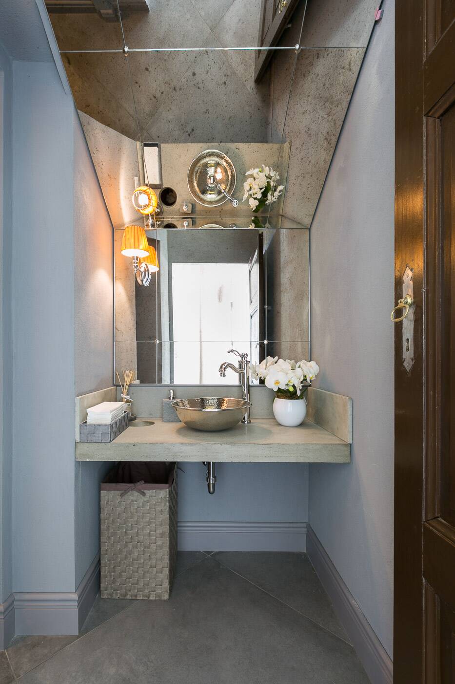 Toilette uomo nei toni del grigio, con lavabo in metallo battuto e specchi anticati