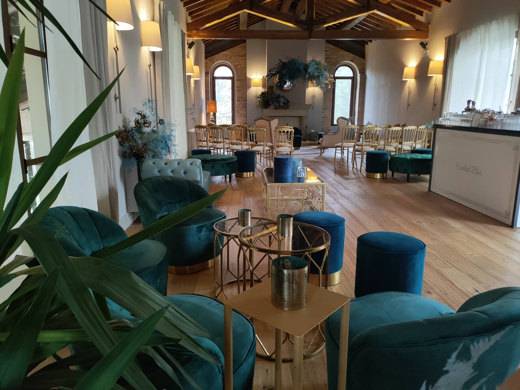 Salone allestito con poltrone lounge in velluto verde e sedute per meeting