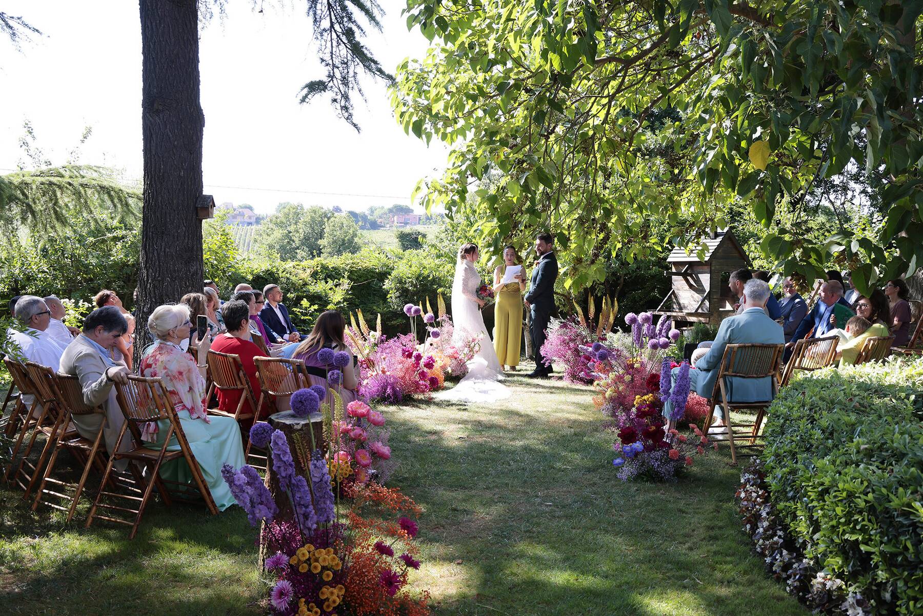Cerimonia in giardino tra fiori colorati e ospiti seduti