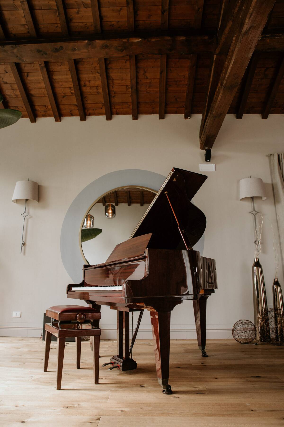 Pianoforte a coda incorniciato dallo specchio rotondo nel Salone del Camino