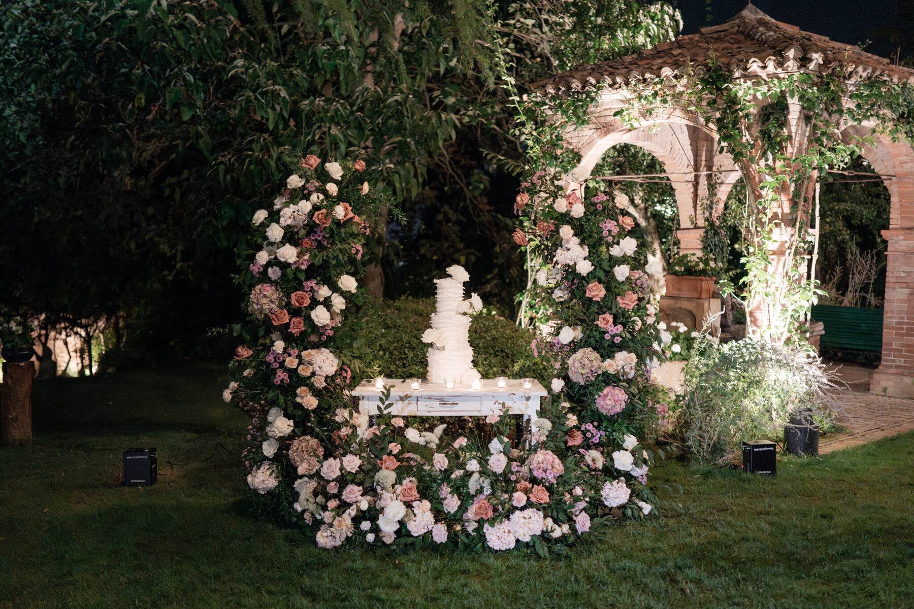 La torta nuziale sotto un arco di rose antiche, di notte