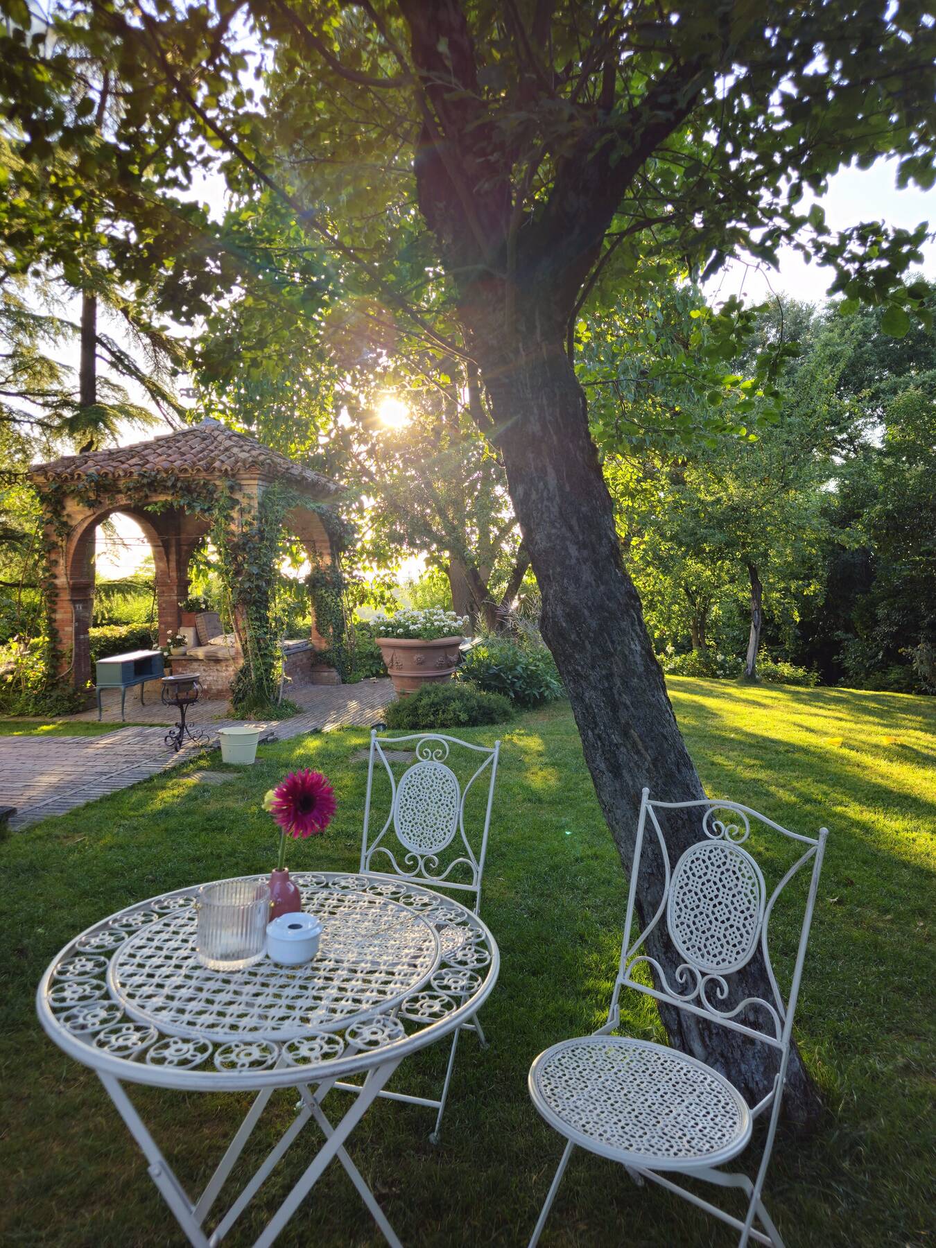 Un angolo di giardino con tavolino e sedie in ferro battuto al tramonto