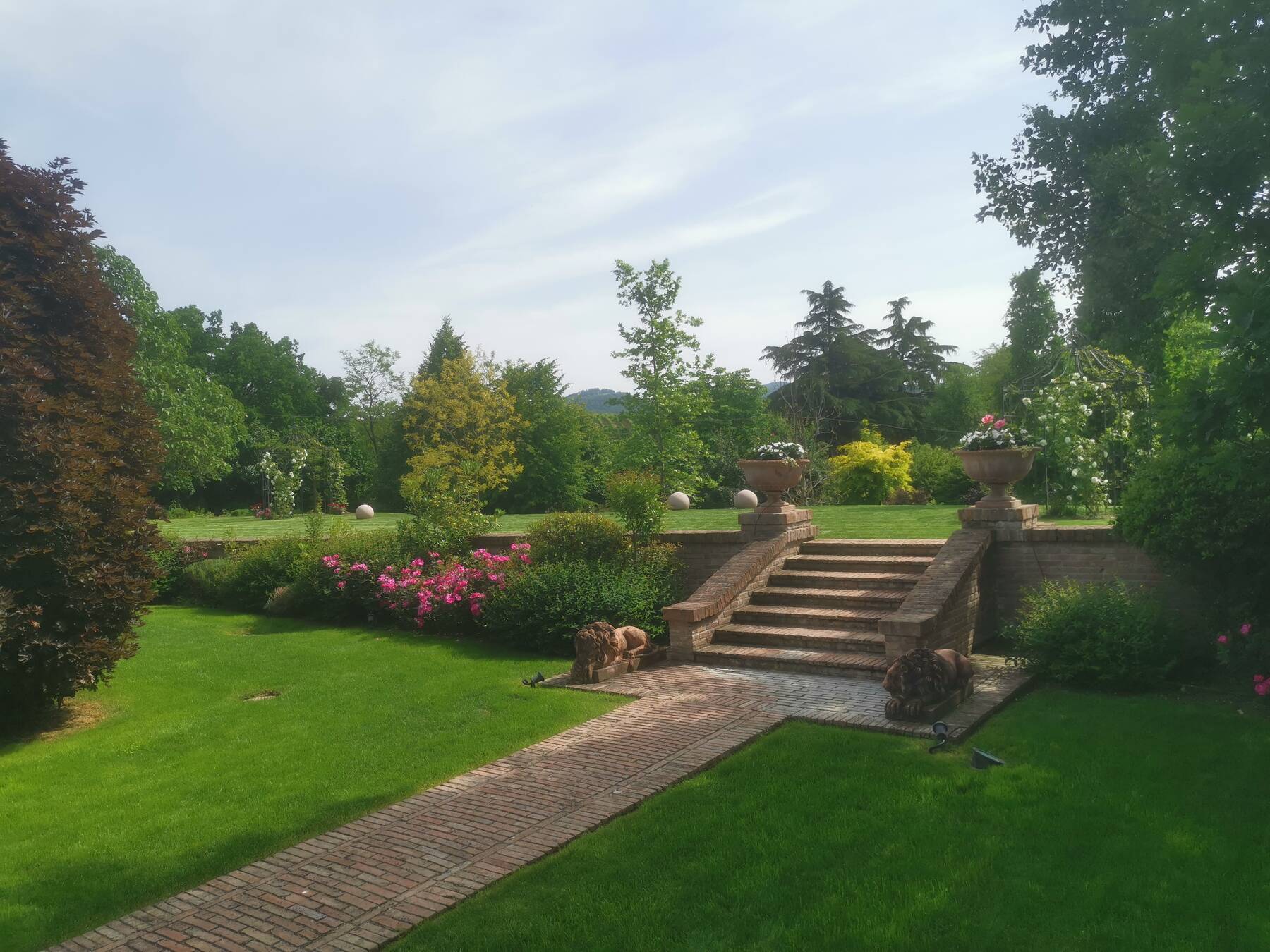 La scalinata in mattoni tra due statue di leoni in pietra, fiancheggiata da rose rampicanti, che collega la Piazzetta delle Rose al Giardino delle Cerimonie