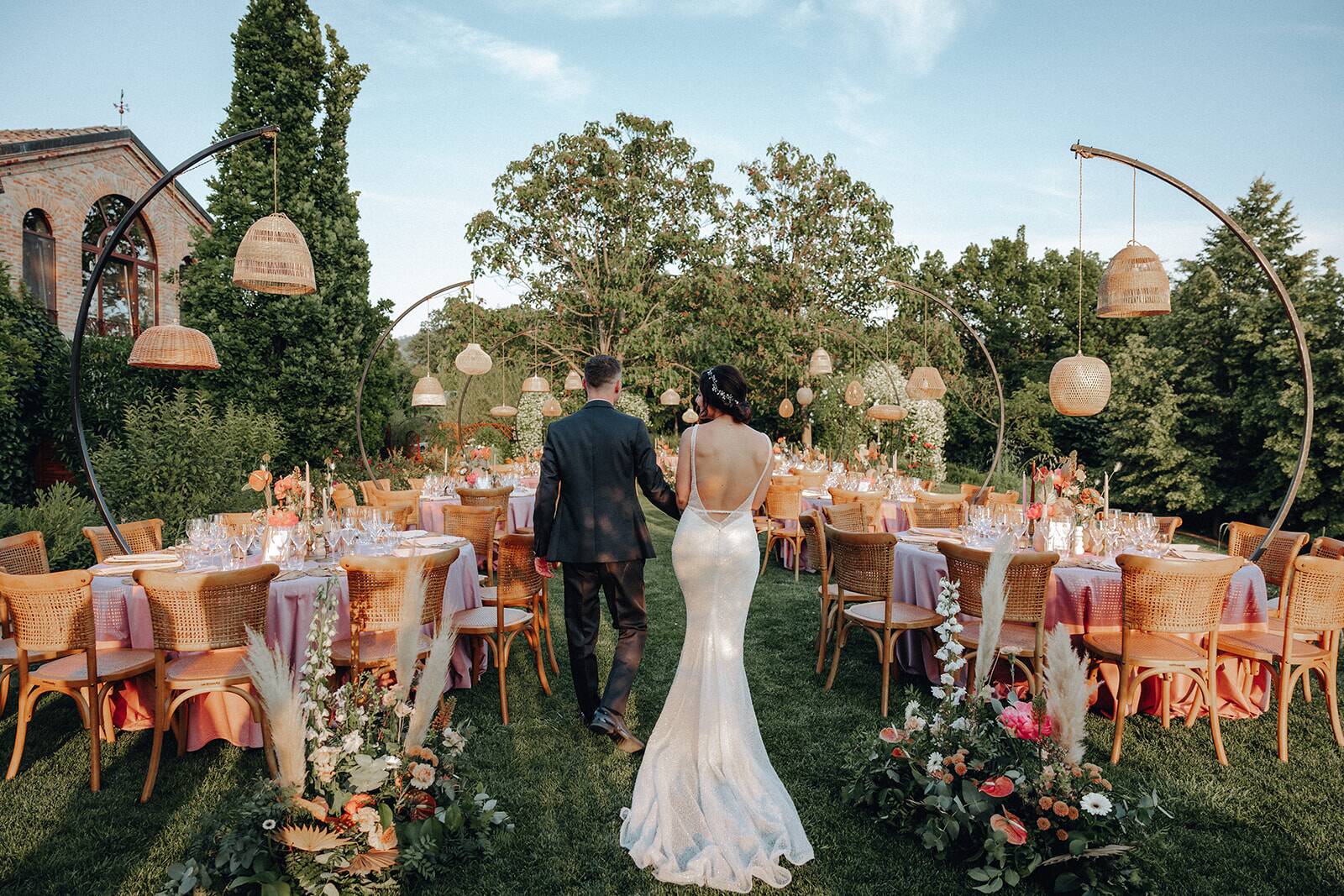 Sposi tra i tavoli in giardino allestiti in stile boho con lanterne rotonde