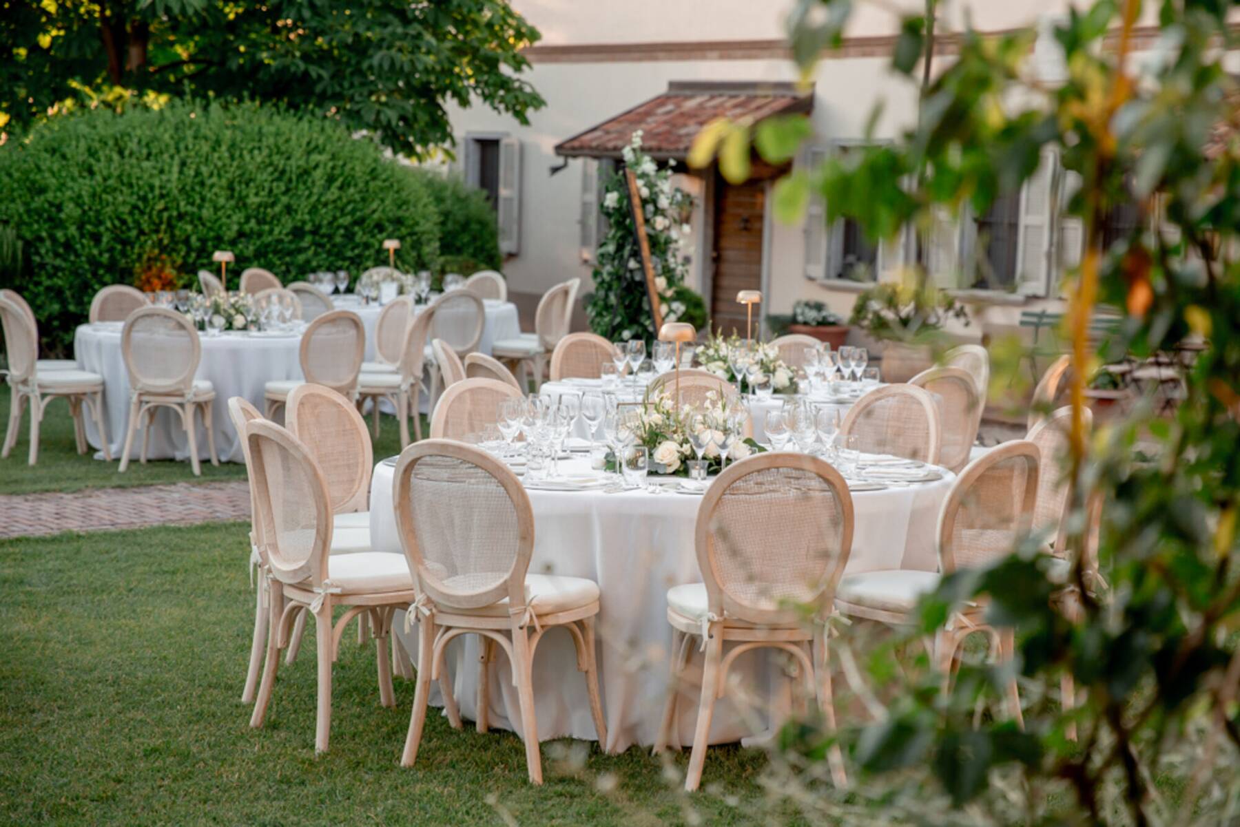 Centrotavola con fiori bianchi e candela sul tavolo apparecchiato in giardino