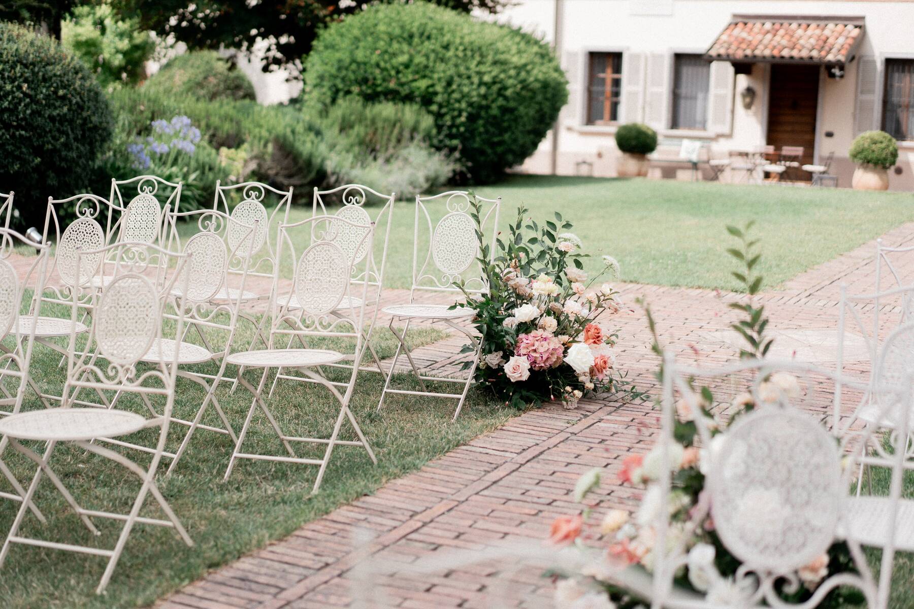 Dettaglio delle sedute bianche e del bouquet lungo la navata